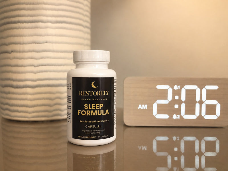 Restorely Sleep Formula capsules on nightstand at night with LED clock